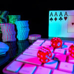 Computer keyboard and quads of four aces, illuminated with pink light on black background. Cards, casino chips and dice close up. Concept of gambling, online betting in casino. Online gambling.